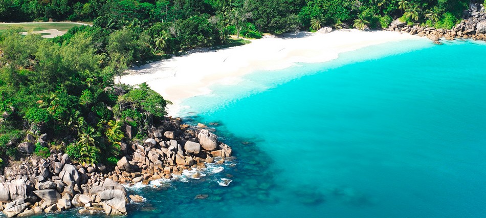 A landscape of rocks, fine sand, lush vegetation and sea in the Seychelles Archipelago